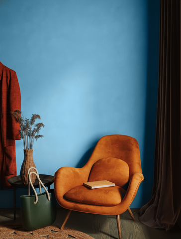 Muted blue colour painted wall photographed behind a vintage rusty orange chair