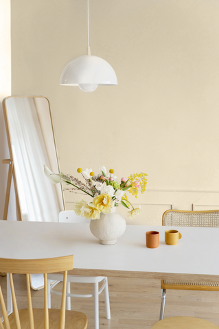 bright and airy dining room with warm sandy coloured walls, white dining table and chairs and a large floor mirror